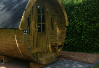 Alojamiento glamping de madera redonda en Parkcamping de Graafschap, Gelderland, rodeado de naturaleza verde.