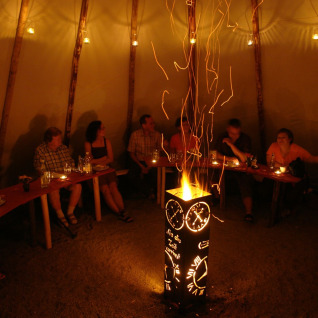 Vista interior de un tipi con personas reunidas alrededor de una fogata en Camping Gieselwerder, Hessen.