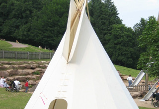 Grote tipi op Camping Gieselwerder in Hessen, geschikt voor glamping, met gras en mensen in de omgeving.