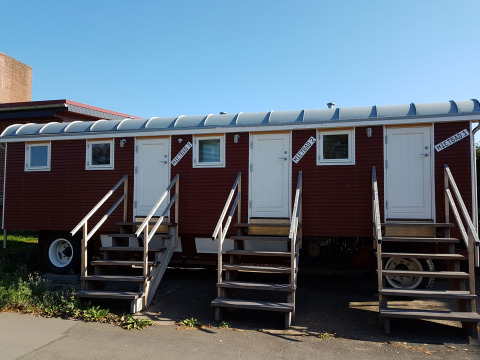 Cabaña móvil roja con tres puertas blancas y escaleras, 'Mietbad', en Camping Gieselwerder, Hessen.
