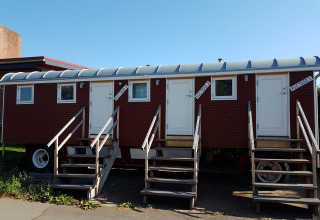 Casa mobile rossa con tre porte bianche e scale, 'Mietbad', al Camping Gieselwerder in Assia.