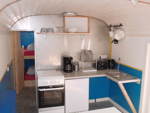Keuken in een glamping pipowagen met stapelbedden, fornuis en keukengerei op Camping Gieselwerder in Hessen.