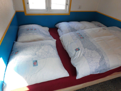 Binnenzicht van een gezellig bed met dubbele dekbedden in glampingverblijf bij Camping Gieselwerder.