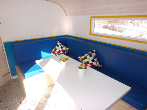 Innenansicht einer Glamping-Unterkunft bei Camping Gieselwerder mit blauer Eckbank und bunten Kissen.