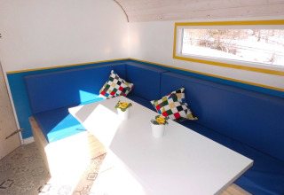 Innenansicht einer Glamping-Unterkunft bei Camping Gieselwerder mit blauer Eckbank und bunten Kissen.