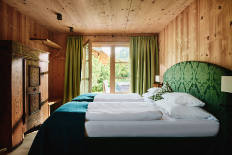 Accogliente camera in legno con tende verdi e vista al HochLeger Chalet Refugium - Chalet Tirol.
