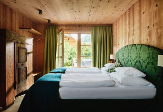 Chambre boisée chaleureuse avec rideaux verts et vue au HochLeger Chalet Refugium - Chalet Tirol.