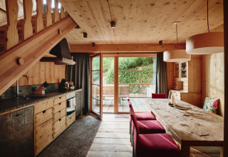 Hyggeligt træinteriør i HochLeger Chalet Refugium - Chalet Tirol med spiseplads og udgang til terrasse.
