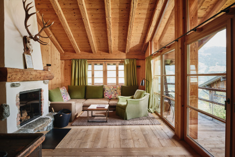 Gezellige woonkamer met open haard en houten interieur in HochLeger Chalet Refugium - Chalet Tirol glamping.