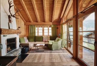 Salon douillet au bois, grande baie vitrée et cheminée au HochLeger Chalet Refugium - Chalet Tirol, glamping.