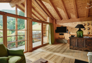 Vue intérieure du HochLeger Chalet Refugium - Chalet Tirol avec bois, grandes fenêtres et vue sur la montagne.