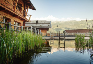HochLeger Chalet Refugium - Chalet Tirol glamping cabin with natural pool, reeds, and mountain backdrop in Austria.