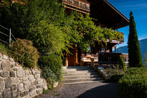 HochLeger Chalet Refugium - Chalet Tirol, luxuriöse Glamping-Unterkunft mit Garten und Holzveranda im Sonnenschein.