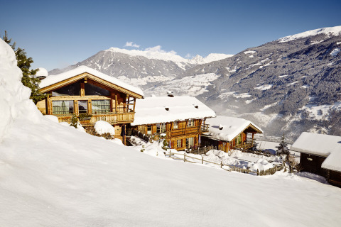 Alloggio glamping HochLeger Chalet Refugium - Chalet Tirol in inverno, chalet in legno e montagne innevate sullo sfondo.