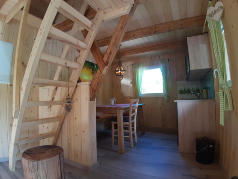 Interno di un lodge glamping al Gallushof, Foresta Nera, Germania, con scala e zona pranzo in legno.