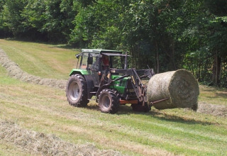 Ein Traktor transportiert eine große Heuballen nahe den Boerderij Gallushof Lodges im Schwarzwald, Deutschland.