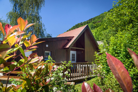 Glamping cabin at Auberge et Chalets de la Wormsa, surrounded by lush greenery in the Vosges, summer.