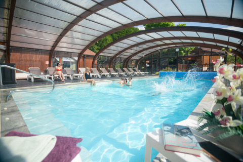 Piscine couverte avec des clients détendus et des fleurs à Auberge et Chalets de la Wormsa - Glamping Vogezen.