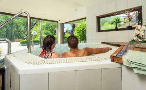 Couple se détend dans un jacuzzi intérieur avec vue sur la nature à Auberge et Chalets de la Wormsa.