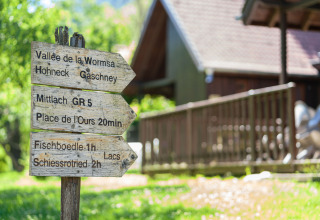 Houten wegwijzer bij Auberge et Chalets de la Wormsa - Glamping Vogezen, met wandelroutes in de natuur.