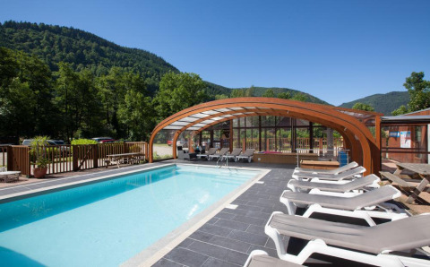Buitenzwembad met ligstoelen en gedeeltelijke overkapping bij Auberge et Chalets de la Wormsa - Glamping Vogezen, omringd door bosrijke heuvels.