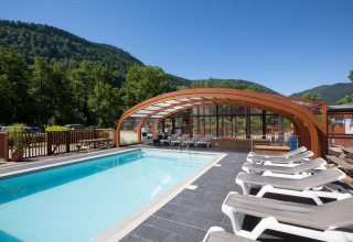 Buitenzwembad met ligstoelen en gedeeltelijke overkapping bij Auberge et Chalets de la Wormsa - Glamping Vogezen, omringd door bosrijke heuvels.