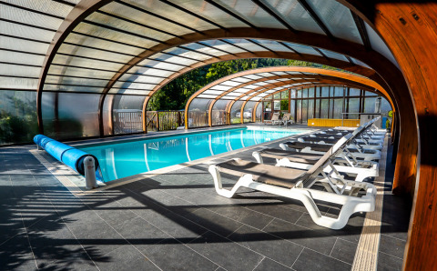 Überdachtes Schwimmbad mit Liegestühlen im Auberge et Chalets de la Wormsa - Glamping Vogezen Camping-Unterkunft.