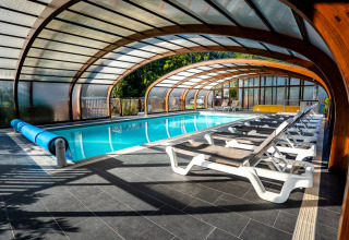 Überdachtes Schwimmbad mit Liegestühlen im Auberge et Chalets de la Wormsa - Glamping Vogezen Camping-Unterkunft.