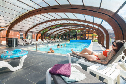 Piscine intérieure avec des clients détendus sur des transats à l'Auberge et Chalets de la Wormsa - Glamping Vogezen.