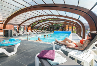 Piscina coperta con ospiti che si rilassano sui lettini all'Auberge et Chalets de la Wormsa - Glamping Vogezen.