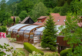 Glamping Auberge et Chalets de la Wormsa con piscina coperta, chalet e natura verde circostante.