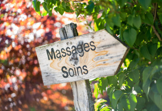 Wooden sign for massages and treatments among trees at Auberge et Chalets de la Wormsa - Glamping Vogezen.