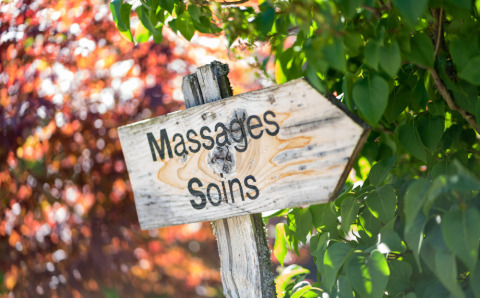 Houten bord voor massages en behandelingen tussen bomen bij Auberge et Chalets de la Wormsa - Glamping Vogezen.