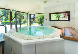 Indoor hot tub at Auberge et Chalets de la Wormsa - Glamping Vogezen with large windows and lush outdoor view.