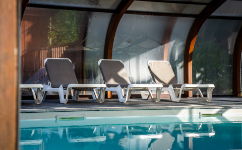 Fire liggestole står ved indendørs pool under glastag hos Auberge et Chalets de la Wormsa - Glamping Vogezen.