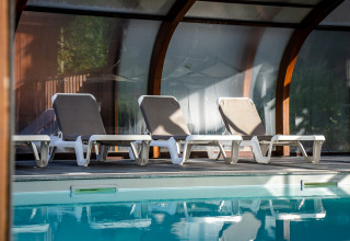 Vier ligstoelen bij het binnenzwembad van Auberge et Chalets de la Wormsa - Glamping Vogezen.