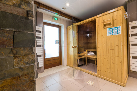 Espace spa intérieur avec sauna en bois et mur en pierre à l'Auberge et Chalets de la Wormsa - Glamping Vogezen.