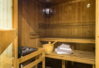 Sauna de madera acogedora con bancos y toallas en Auberge et Chalets de la Wormsa - Glamping Vogezen.
