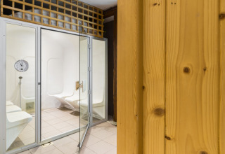 Bagno turco moderno con panche bianche e porta in vetro presso Auberge et Chalets de la Wormsa - Glamping Vogezen.