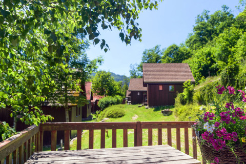 View of cozy wooden glamping cabins and colorful flowers at Auberge et Chalets de la Wormsa in the Vosges.