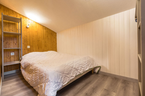Dormitorio en Auberge et Chalets de la Wormsa Glamping Vogezen con cama doble y paredes de paneles de madera.
