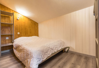 Soveværelse i Auberge et Chalets de la Wormsa Glamping Vogezen med dobbeltseng og træpaneler på væggene.