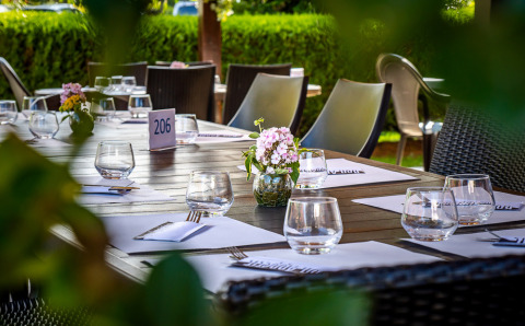 Udendørs restaurantbord dækket til middag på Auberge et Chalets de la Wormsa - Glamping Vogezen, omgivet af grøn hæk.