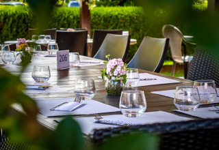 Tavolo da ristorante all'aperto apparecchiato presso Auberge et Chalets de la Wormsa - Glamping Vogezen, circondato dal verde.