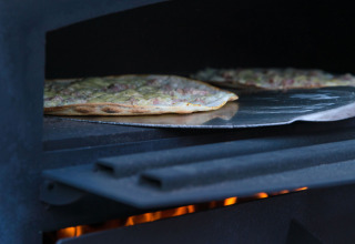 Una pizza se hornea en horno de leña en Auberge et Chalets de la Wormsa - Glamping Vogezen.