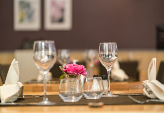 Elegante tafelopstelling bij Auberge et Chalets de la Wormsa - Glamping Vogezen met wijnglazen en bloem.