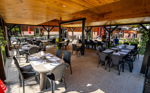 Area pranzo all'aperto presso Auberge et Chalets de la Wormsa - Glamping Vogezen con tavoli apparecchiati sotto tettoia.