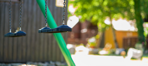 Empty swings at Auberge et Chalets de la Wormsa - Glamping Vogezen, with greenery and sunlight in the background.