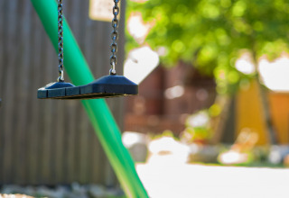 Empty swings at Auberge et Chalets de la Wormsa - Glamping Vogezen, with greenery and sunlight in the background.