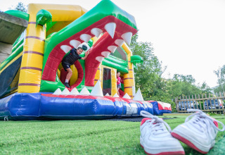 Bambini giocano su un gonfiabile presso Auberge et Chalets de la Wormsa - Glamping Vogezen, scarpe sull’erba davanti.